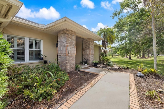 exterior space with brick siding, a yard, and stucco siding