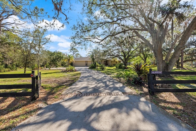 view of front of house featuring an attached garage, driveway, a fenced front yard, and a front yard