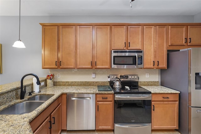 kitchen with pendant lighting, decorative backsplash, appliances with stainless steel finishes, a sink, and light stone countertops