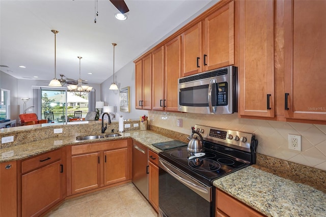 kitchen with a peninsula, brown cabinetry, stainless steel appliances, and a sink