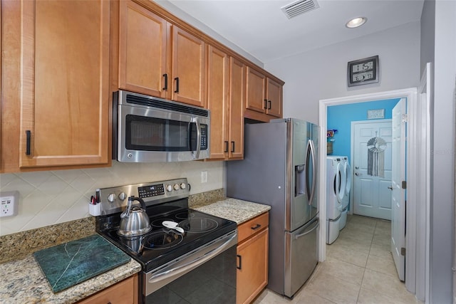 kitchen with appliances with stainless steel finishes, visible vents, washing machine and clothes dryer, and tasteful backsplash