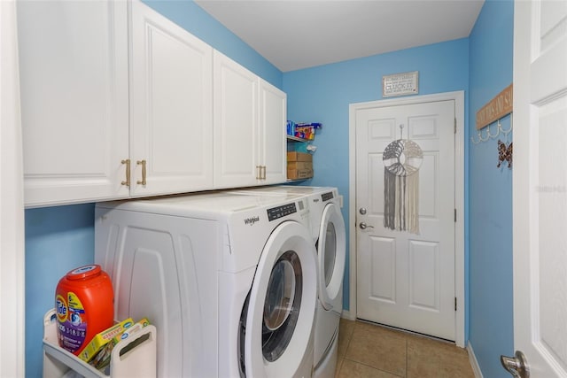 clothes washing area with light tile patterned floors, washer and clothes dryer, cabinet space, and baseboards