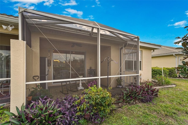 view of side of home featuring a lanai, ceiling fan, and stucco siding