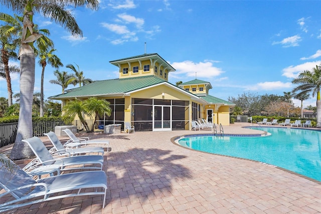 community pool with a sunroom, a patio, and fence