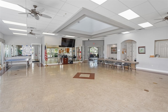 miscellaneous room with visible vents, arched walkways, baseboards, a towering ceiling, and ceiling fan