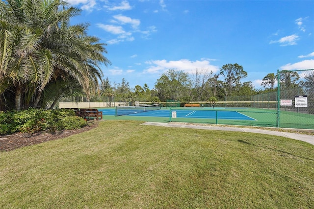 view of sport court with fence and a yard