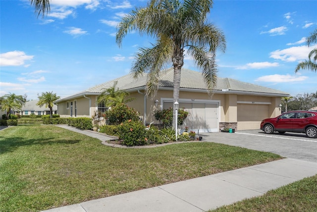 view of side of home featuring a tile roof, a yard, stucco siding, an attached garage, and driveway