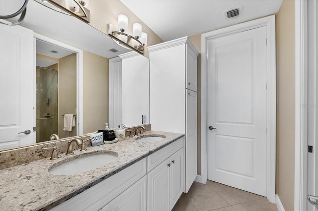 bathroom featuring a shower with shower door, a sink, visible vents, and tile patterned floors