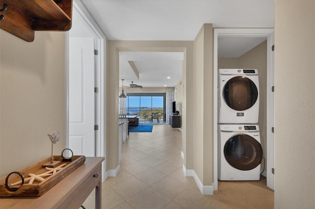 washroom with stacked washer / drying machine, baseboards, and light tile patterned floors