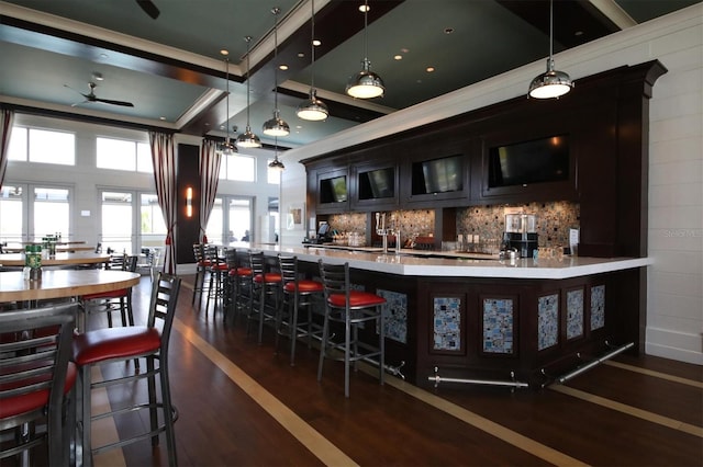 bar with beverage cooler, decorative backsplash, dark wood-style flooring, hanging light fixtures, and indoor wet bar