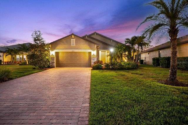 view of front of property featuring a front lawn, decorative driveway, an attached garage, and stucco siding