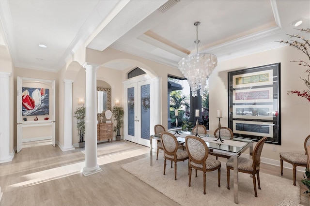 dining space with light wood-type flooring, visible vents, french doors, a raised ceiling, and ornate columns