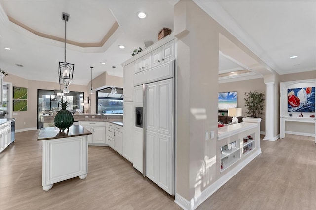 kitchen featuring ornate columns, a peninsula, a tray ceiling, and paneled built in fridge