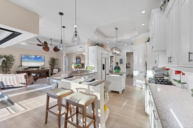 kitchen with white cabinetry, a tray ceiling, crown molding, and arched walkways