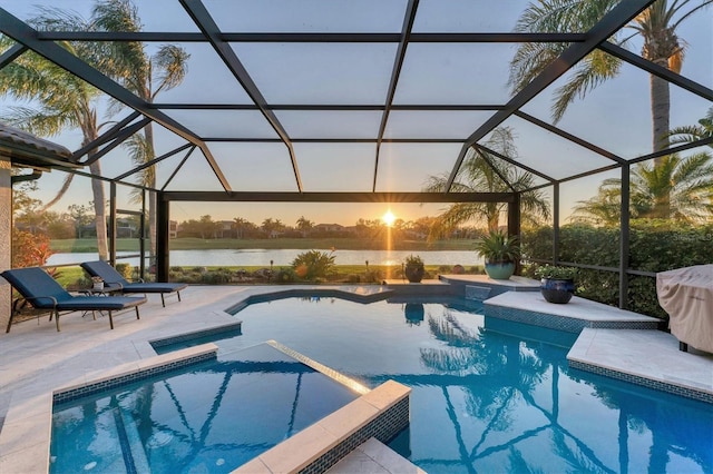 pool at dusk featuring a patio, a pool with connected hot tub, a lanai, and a water view