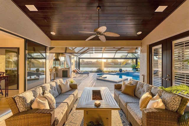 view of patio / terrace with ceiling fan, a water view, a lanai, an outdoor hangout area, and an outdoor pool