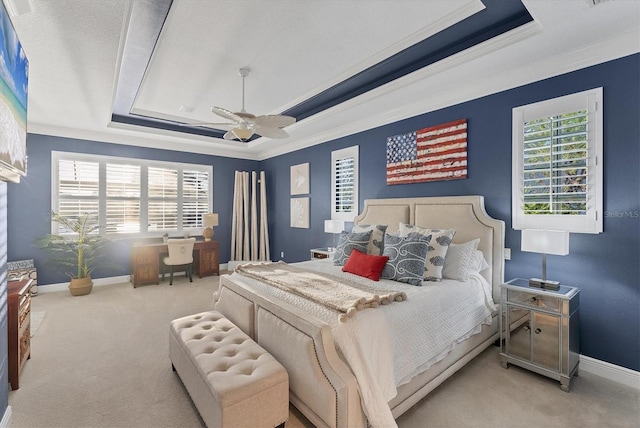 carpeted bedroom featuring multiple windows, a raised ceiling, baseboards, and ceiling fan