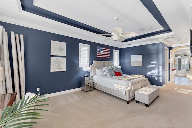 bedroom with a ceiling fan, baseboards, ornamental molding, a raised ceiling, and carpet flooring