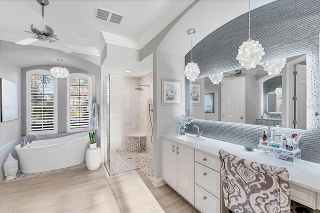 bathroom featuring visible vents, ceiling fan with notable chandelier, wood finished floors, a tile shower, and crown molding