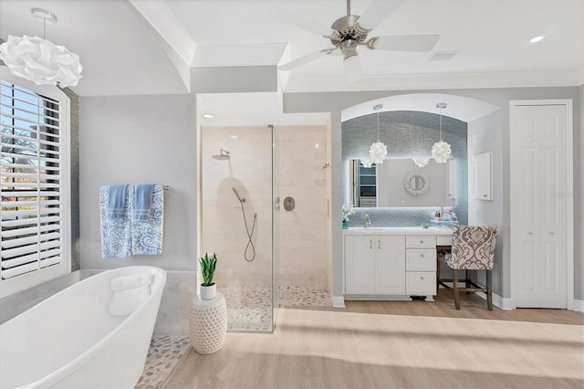 full bath featuring a walk in shower, wood finished floors, crown molding, a soaking tub, and vanity