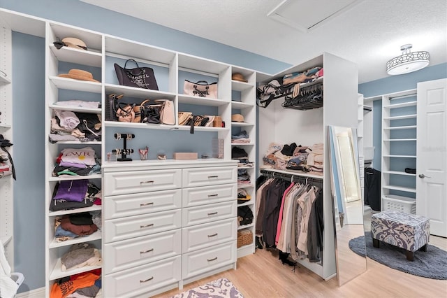 spacious closet with light wood finished floors and attic access