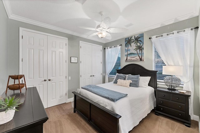 bedroom with ceiling fan, baseboards, two closets, and ornamental molding