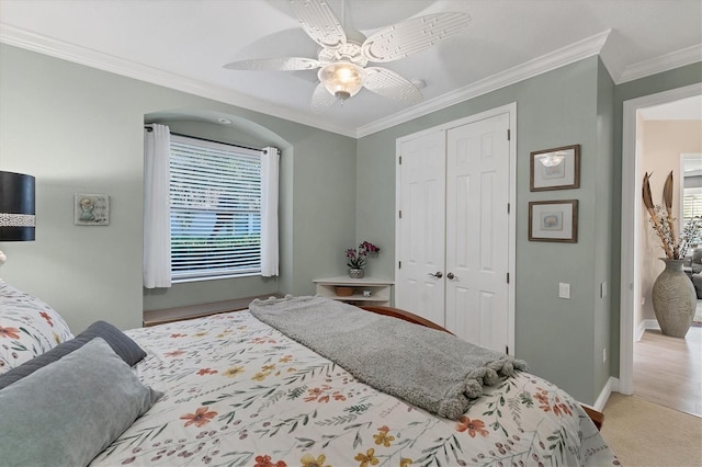 bedroom with baseboards, carpet floors, ceiling fan, a closet, and crown molding