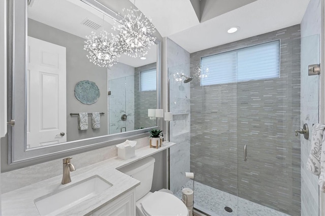 full bathroom featuring visible vents, toilet, a notable chandelier, a shower stall, and vanity