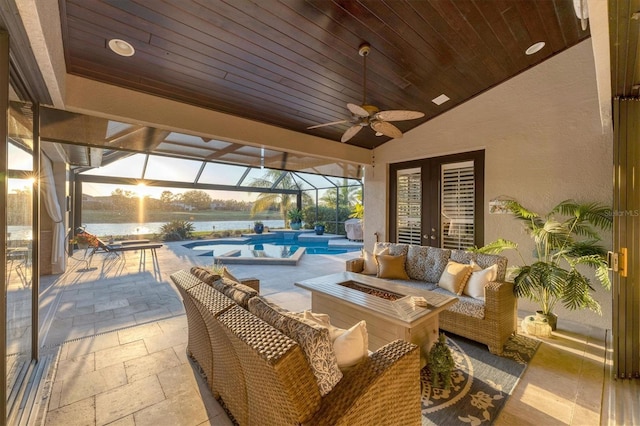 view of patio featuring glass enclosure, a ceiling fan, an outdoor pool, an outdoor living space with a fire pit, and a water view