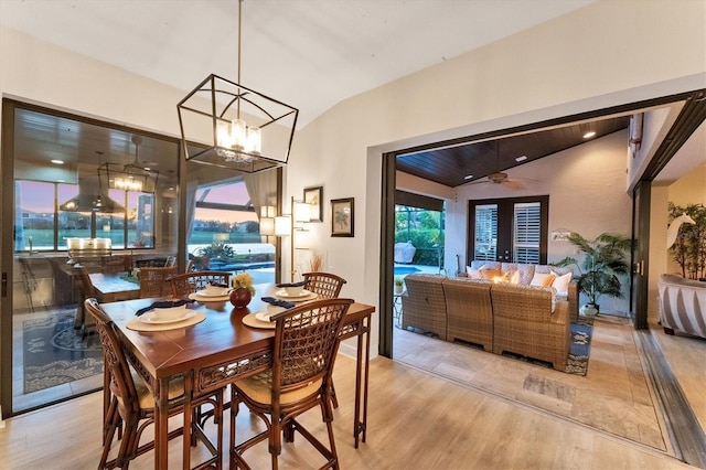 dining space featuring light wood finished floors, an inviting chandelier, and vaulted ceiling