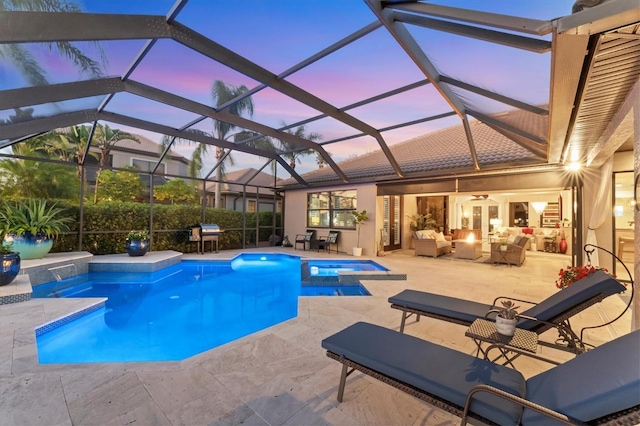 pool at dusk with an outdoor living space, a pool with connected hot tub, glass enclosure, and a patio