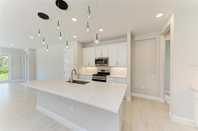 995 Waterline Ct, Sarasota, FL 34240 - kitchen with appliances with stainless steel finishes, white cabinets, a sink, an island with sink, and light stone countertops