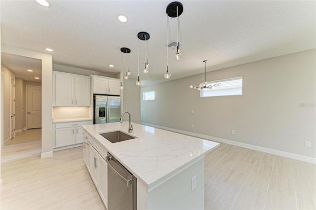 995 Waterline Ct, Sarasota, FL 34240 - kitchen with pendant lighting, stainless steel appliances, white cabinets, a sink, and an island with sink