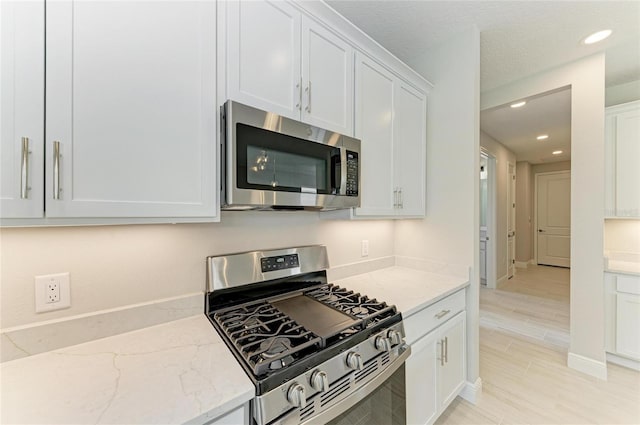 995 Waterline Ct, Sarasota, FL 34240 - kitchen featuring light stone counters, recessed lighting, white cabinetry, appliances with stainless steel finishes, and light wood finished floors