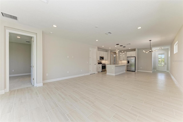 995 Waterline Ct, Sarasota, FL 34240 - unfurnished living room with recessed lighting, visible vents, baseboards, and an inviting chandelier