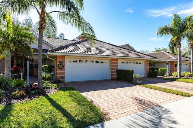 single story home with a garage, a tiled roof, and decorative driveway