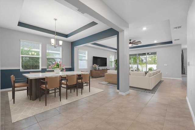 dining area with light tile patterned floors, visible vents, a tray ceiling, and a wealth of natural light