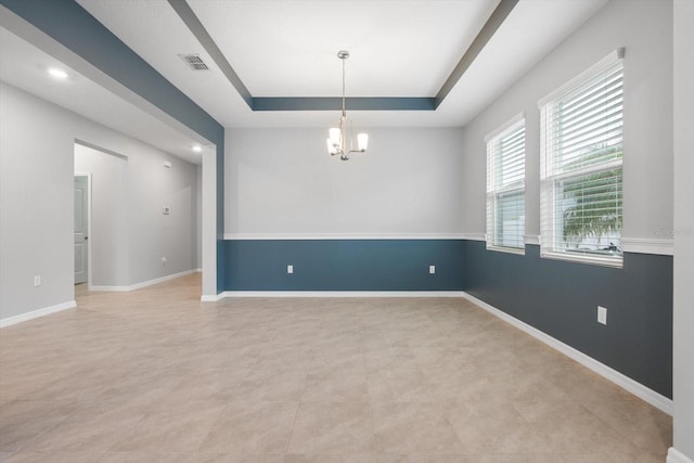 spare room featuring a tray ceiling, visible vents, baseboards, and an inviting chandelier