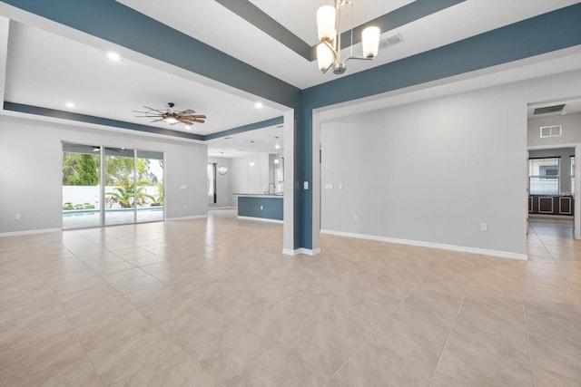 unfurnished living room with light tile patterned floors, ceiling fan with notable chandelier, a sink, baseboards, and a raised ceiling