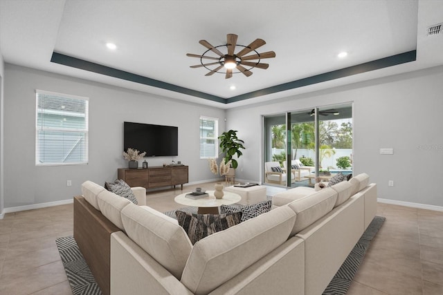 living area with baseboards, a tray ceiling, a ceiling fan, and recessed lighting