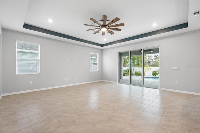 empty room with a tray ceiling, ceiling fan, baseboards, and recessed lighting