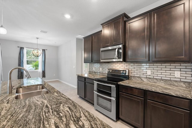 kitchen featuring visible vents, dark stone counters, appliances with stainless steel finishes, a sink, and backsplash