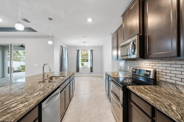 kitchen with light tile patterned floors, tasteful backsplash, appliances with stainless steel finishes, a sink, and dark brown cabinets