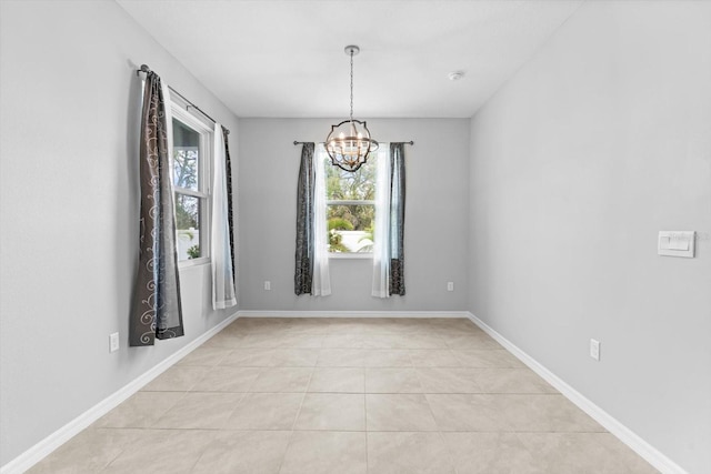 empty room featuring light tile patterned floors, baseboards, and a chandelier