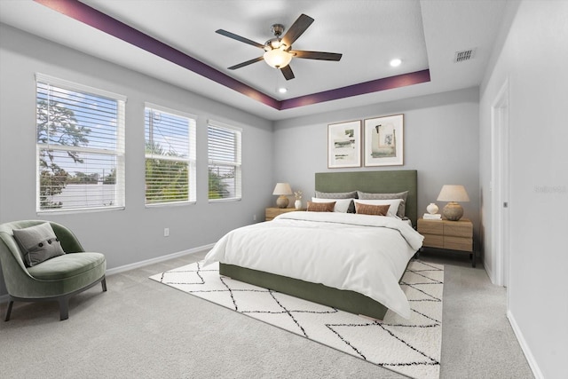 bedroom with baseboards, visible vents, a tray ceiling, and light colored carpet