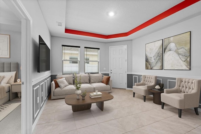 living area featuring light tile patterned floors, visible vents, and a raised ceiling