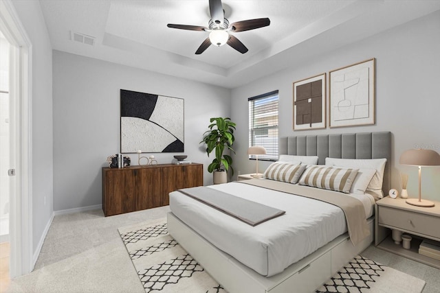 bedroom with light carpet, visible vents, baseboards, and a raised ceiling