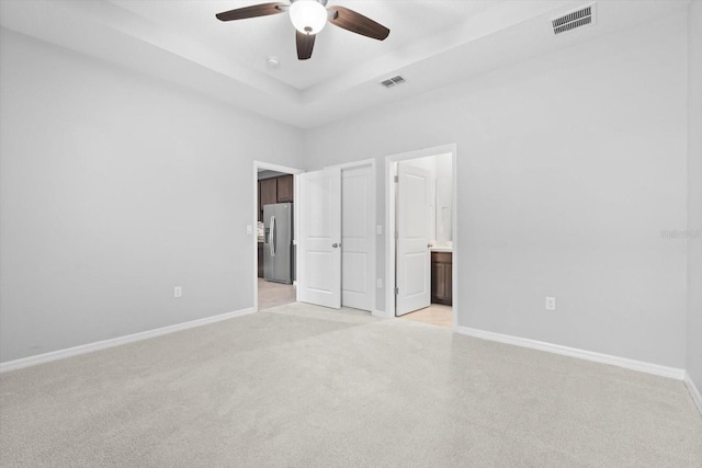 unfurnished bedroom featuring stainless steel fridge, visible vents, a raised ceiling, and baseboards