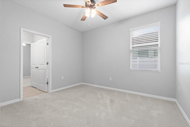 carpeted empty room with a ceiling fan and baseboards