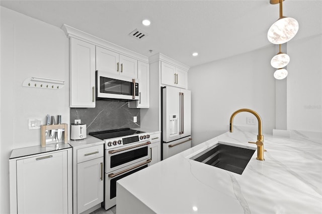 kitchen with white appliances, tasteful backsplash, visible vents, white cabinets, and a sink